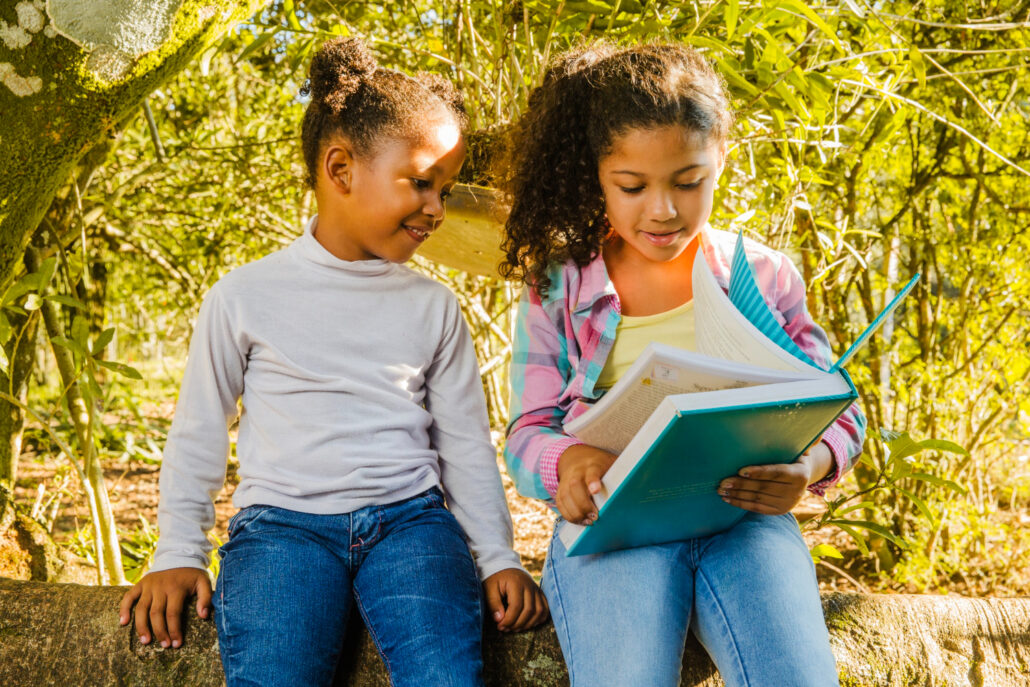 Dos niñas leyendo un libro en un entorno natural